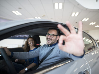 Happy customer buying new car at dealership.
